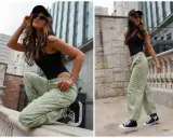 Modna kobieta w zielonych spodniach cargo i czarnym body, prezentująca miejskie stylizacje.