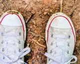Brudne białe trampki na ziemi. Czas dowiedzieć się, jak wyczyścić białe podeszwy, by znów lśniły!