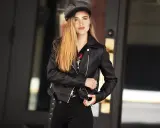 Dziewczyna w czarnej ramonesce i czapce, z długimi blond włosami, emanuje rockowym, glam rock stylem.