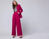 Elegancka stylizacja na chrzciny ze spodniami: fuksjowy garnitur z szerokimi nogawkami i bluzka w panterkę.