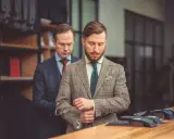 Mężczyzna w garniturze Hugo Boss poprawia mankiet w butiku. Różnica między Hugo a Hugo Boss jest subtelna, ale widoczna w jakości.
