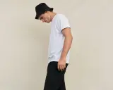Chłopak w czarnym kapeluszu i białej koszulce, z czarnymi spodniami, prezentuje styl skate girl.