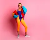 Kobieta w neonowym stroju kąpielowym, pomarańczowych legginsach i kolorowej kurtce, stylizacja inspirowana modą damską lat 90.