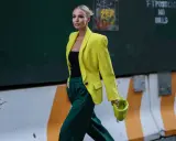 Kobieta w żółtej marynarce i zielonych spodniach, z limonkową torebką. Jej stylizacja to prawdziwe koło kolorów ubrania, łączące energię i elegancję.