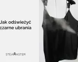 Jak odświeżyć czarne ubrania parownicą? Dymiąca czarna sukienka na wieszaku, ręka trzymająca parownicę.