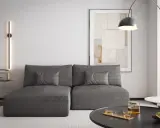 Nowoczesny salon z szarą kanapą, na ścianie pionowa lampa emitująca zielone światło. Czy zielony pasuje do szarego? Tak, tworzy przytulną atmosferę.