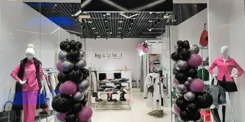 By o la la...! Kto jest właścicielem tego sklepu z modnymi ubraniami? Balony w kolorach czarnym, różowym i srebrnym ozdabiają wejście.
