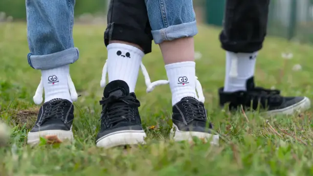 Zabawne skarpetki z postaciami wychodzą spod podwiniętych nogawek jeansów i czarnych spodni. Oto jak nosić skarpetki na spodniach w oryginalny sposób.