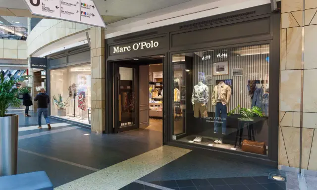 Sklep Marc O'Polo w centrum handlowym. Elegancka witryna prezentuje męskie ubrania, a w środku widać manekiny w stylowych strojach.