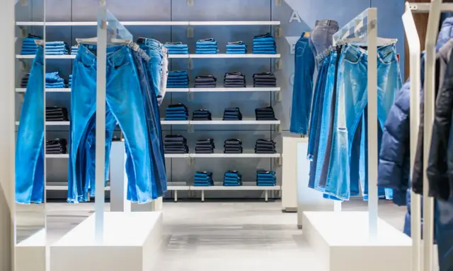 Sklep z jeansami G-Star RAW. Wieszaki uginają się pod ciężarem niebieskich spodni, na półkach poukładane są kolejne pary.