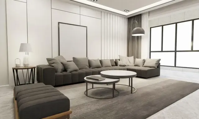 Nowoczesny salon z szarą sofą, dwoma stolikami kawowymi i dywanem. Wnętrze emanuje **quiet luxury**, gdzie każdy element jest dopracowany w subtelny sposób.