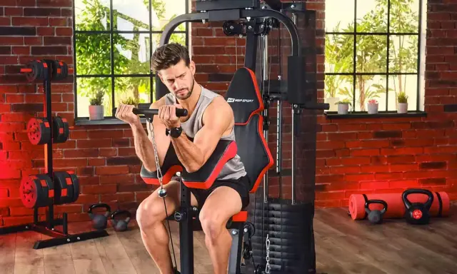 Mężczyzna ćwiczy biceps na domowej siłowni. Sprzęt i akcesoria, jak hantle i kettlebelle, to dowód na to, że polskie marki sportowe oferują wszystko, co potrzebne do treningu.