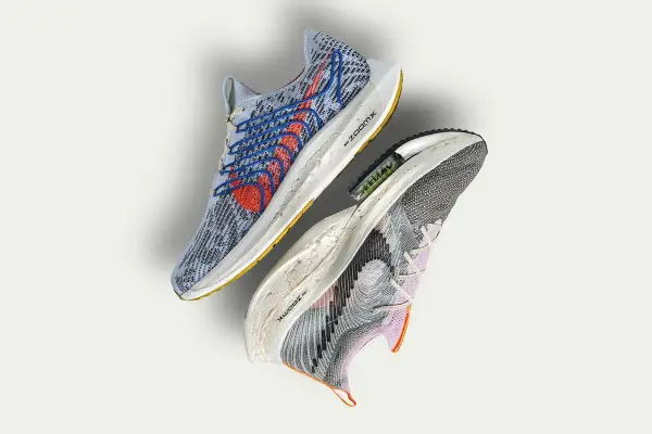 Dwa buty sportowe Nike, jeden niebieski z czerwonymi akcentami, drugi szaro-fioletowy. To przyszłość biegania z Nike Move to Zero.