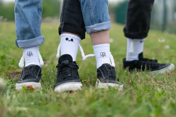 Zabawne skarpetki z postaciami wychodzą spod podwiniętych nogawek jeansów i czarnych spodni. Oto jak nosić skarpetki na spodniach w oryginalny sposób.