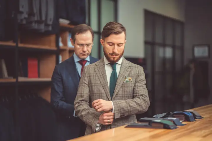 Mężczyzna w garniturze Hugo Boss poprawia mankiet w butiku. Różnica między Hugo a Hugo Boss jest subtelna, ale widoczna w jakości.